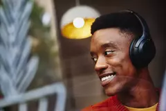 Man with headphone smiling away and looking outside a window