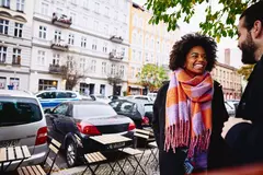 Smiling male and female having a conversation, outside.
