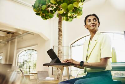 Woman looking away while sitting at table working on a tablet.