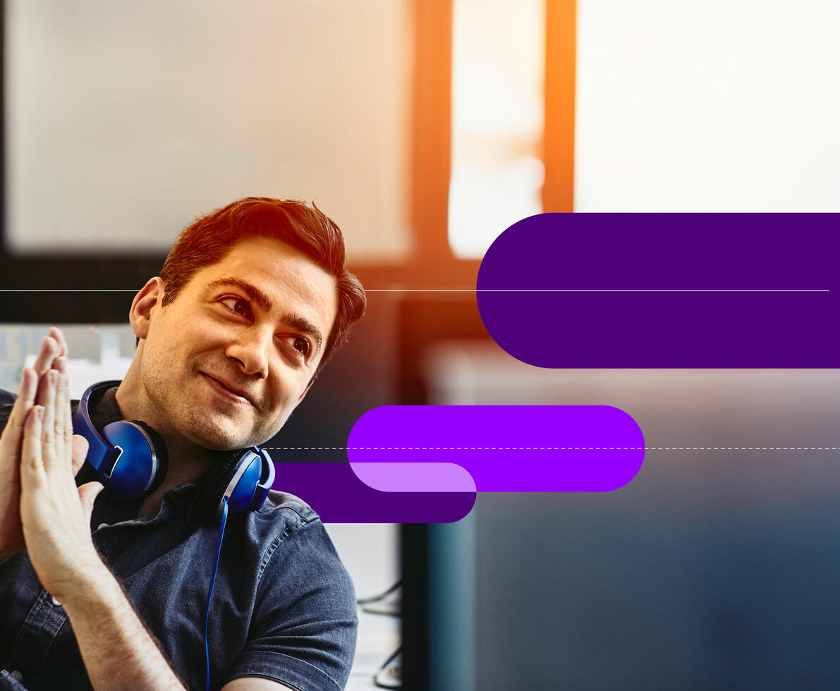 A smiling man with headphones on his neck