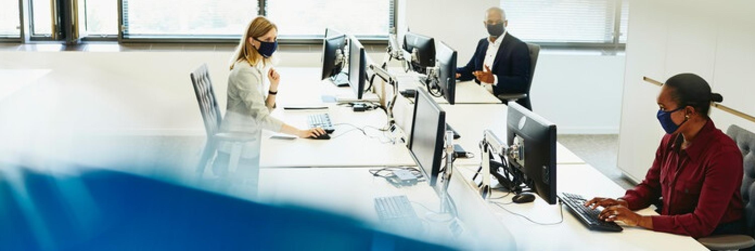 three colleagues wearing masks in the office