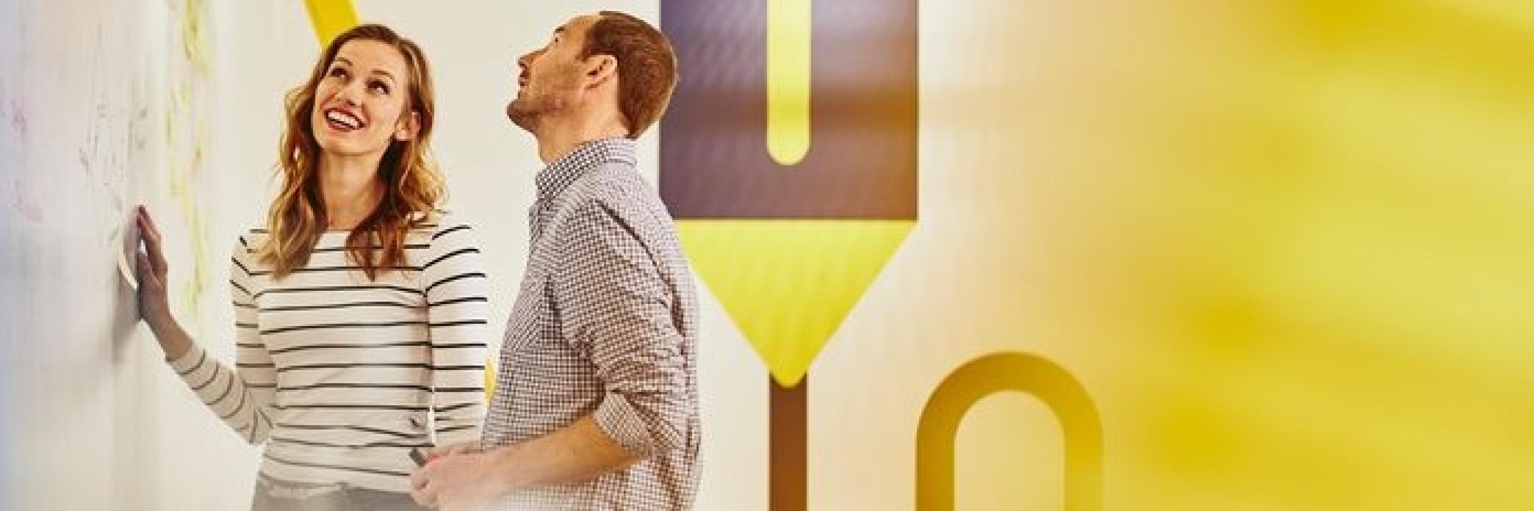 a woman and a man standing by a wall smiling